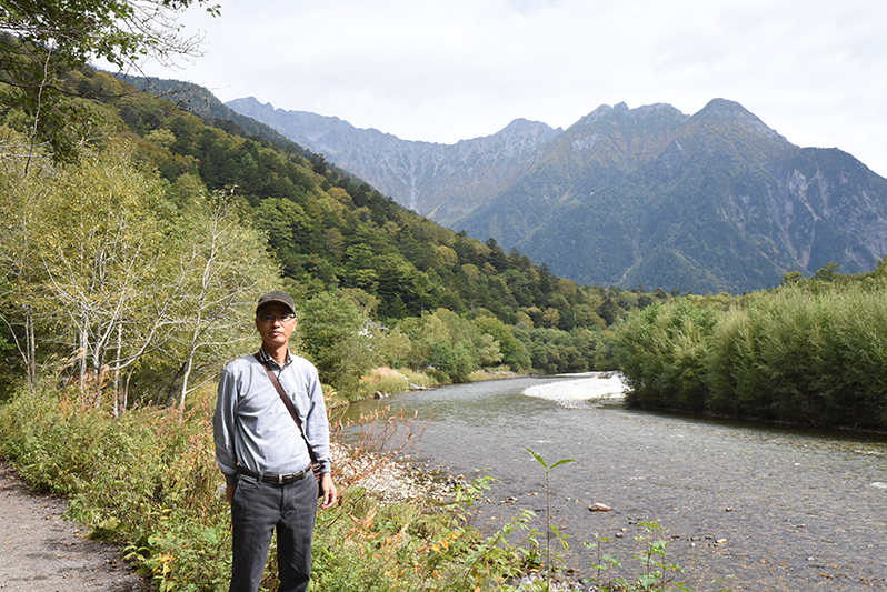川をバックに写真を撮る代表