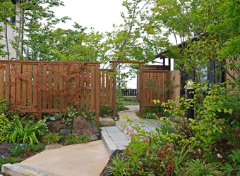 くぐり門の向こうに芝生の庭が広がるアプローチの景。