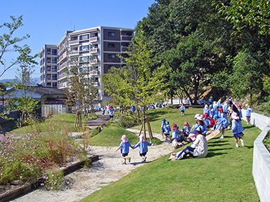 起伏のある芝生と遊歩道が整備され、子どもたちが思い思いに遊んでいる様子。