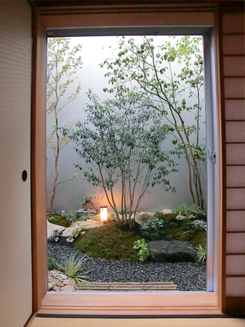 施工後の和室からの眺め。雑木と石・苔で構成された落ち着いた庭。