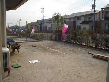 新築直後でまだ何も植栽されていない、土のままの庭の全景。