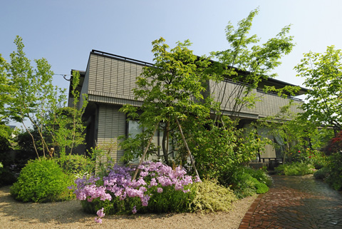 雑木と花に彩られた、緑豊かな玄関アプローチの施工後外観。