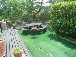 ウッドデッキ奥にテーブルとイスが置かれた施工前のテラス。