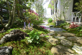 石敷きの小径と周囲の植栽がつくる落ち着いたアプローチ空間。