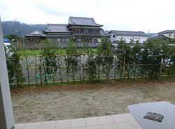 施工前のダイニング前の景色。生垣と空き地が広がる眺め。